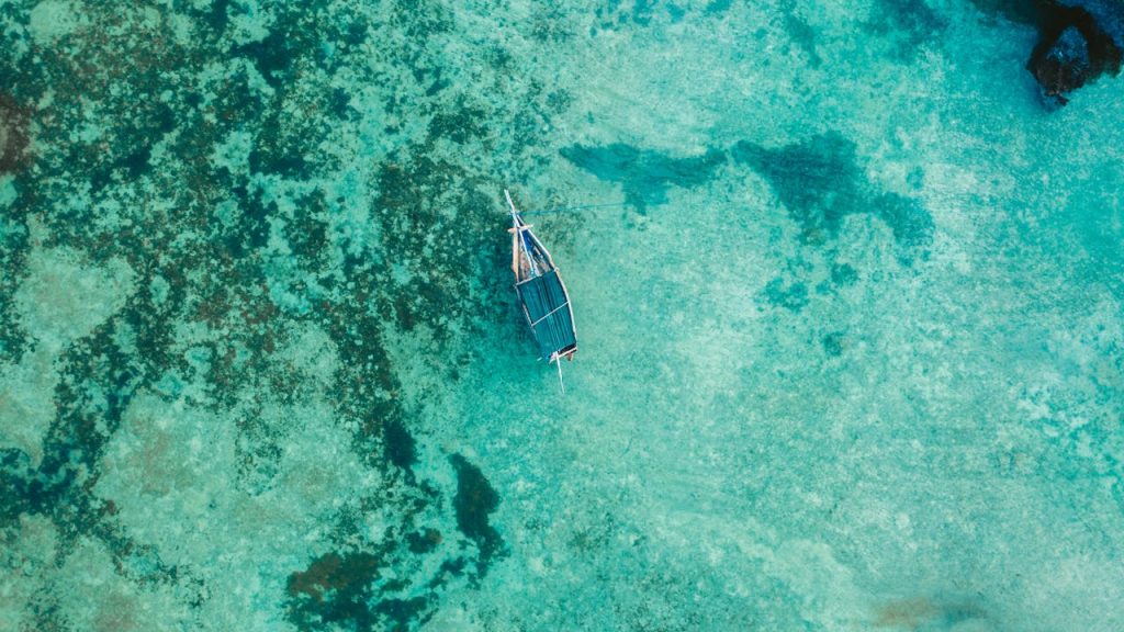 The Art of Drawing Readers In: Your attractive post title goes here Drone shot of a boat floating in clear turquoise waters of Zanzibar, Tanzania. Serene and scenic top view.